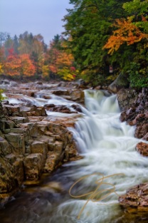 Vertical image of Rocky Gorge on the Swift River in the White Mountains of New Hampshire. Vibrant fall foliage can be seen on the far bank above the gorge.