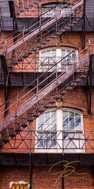 The zigzag of the rusty iron fire escape on an old brick mill building